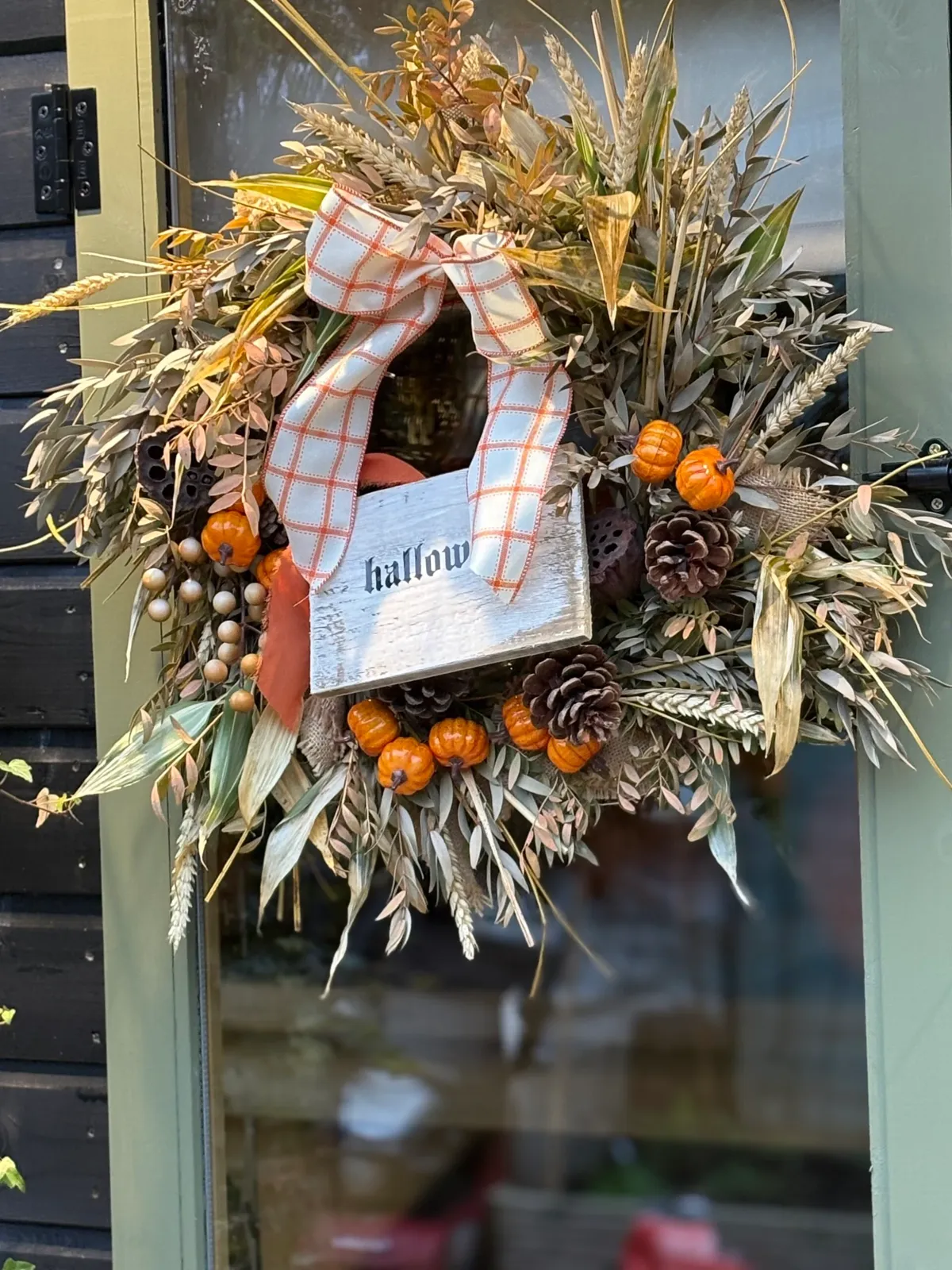 Autumn wreath with wheat, mini pumpkins, pine cones and a gingham bow