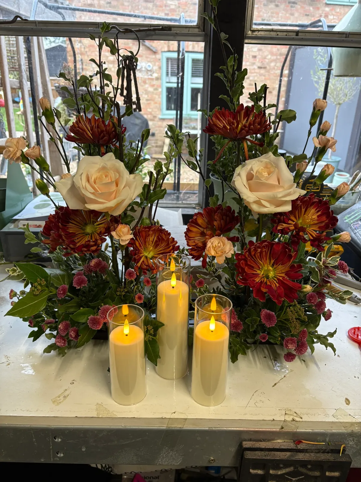 Autumn memorial arrangement with chrysanthemums, roses and candles