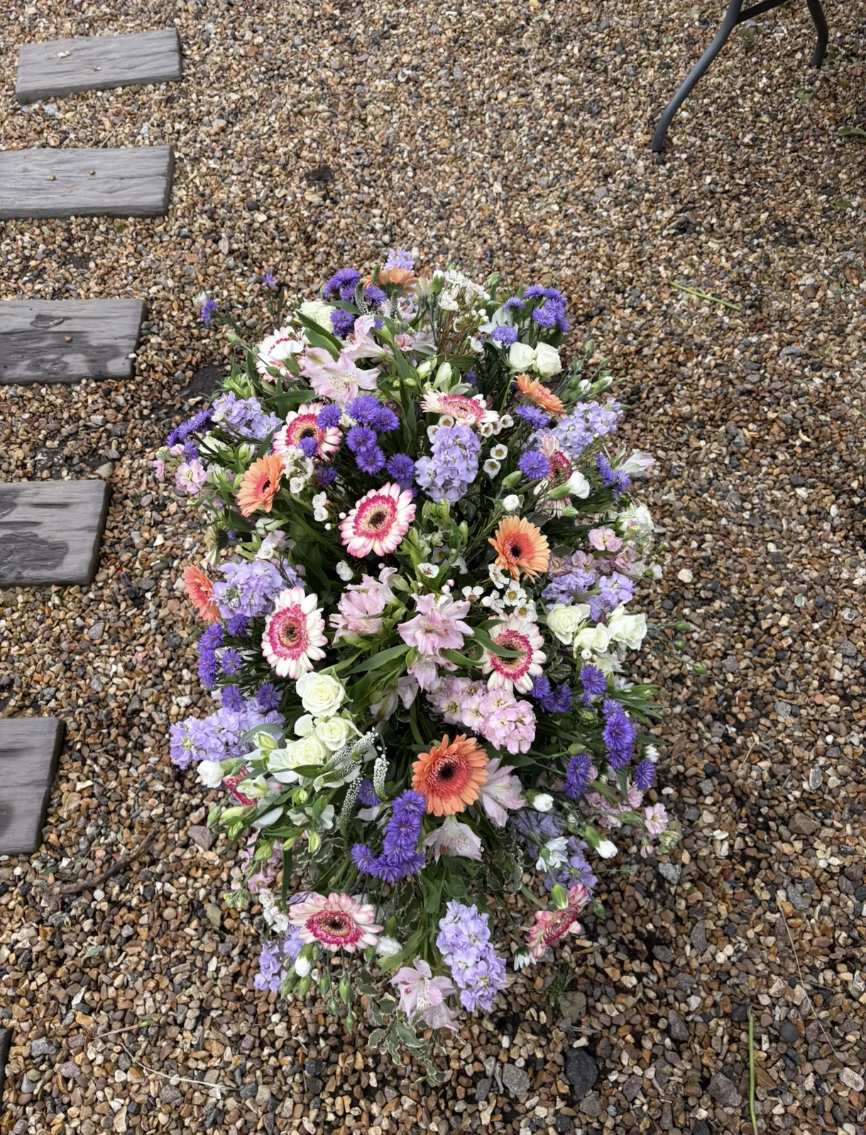 Casket spray of gerberas, stocks and roses in lilac, pink and peach