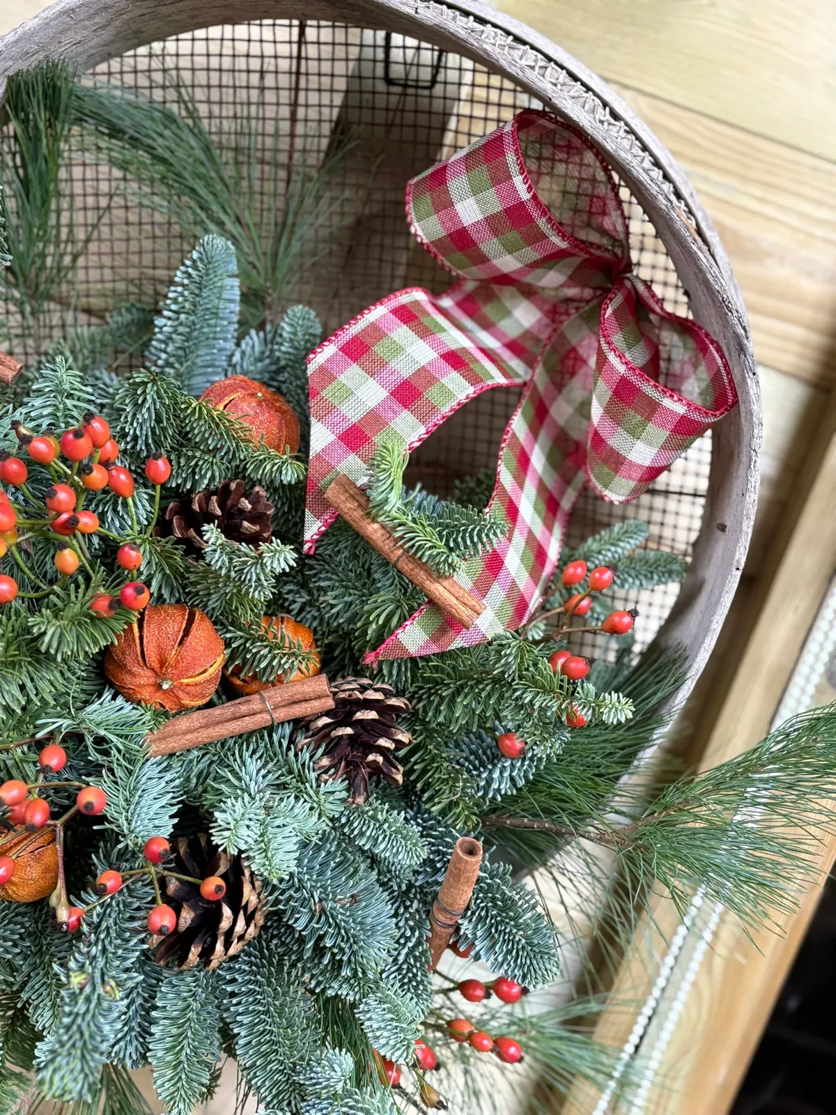 Rustic Christmas sieve with fir, rosehips, dried oranges and cinnamon