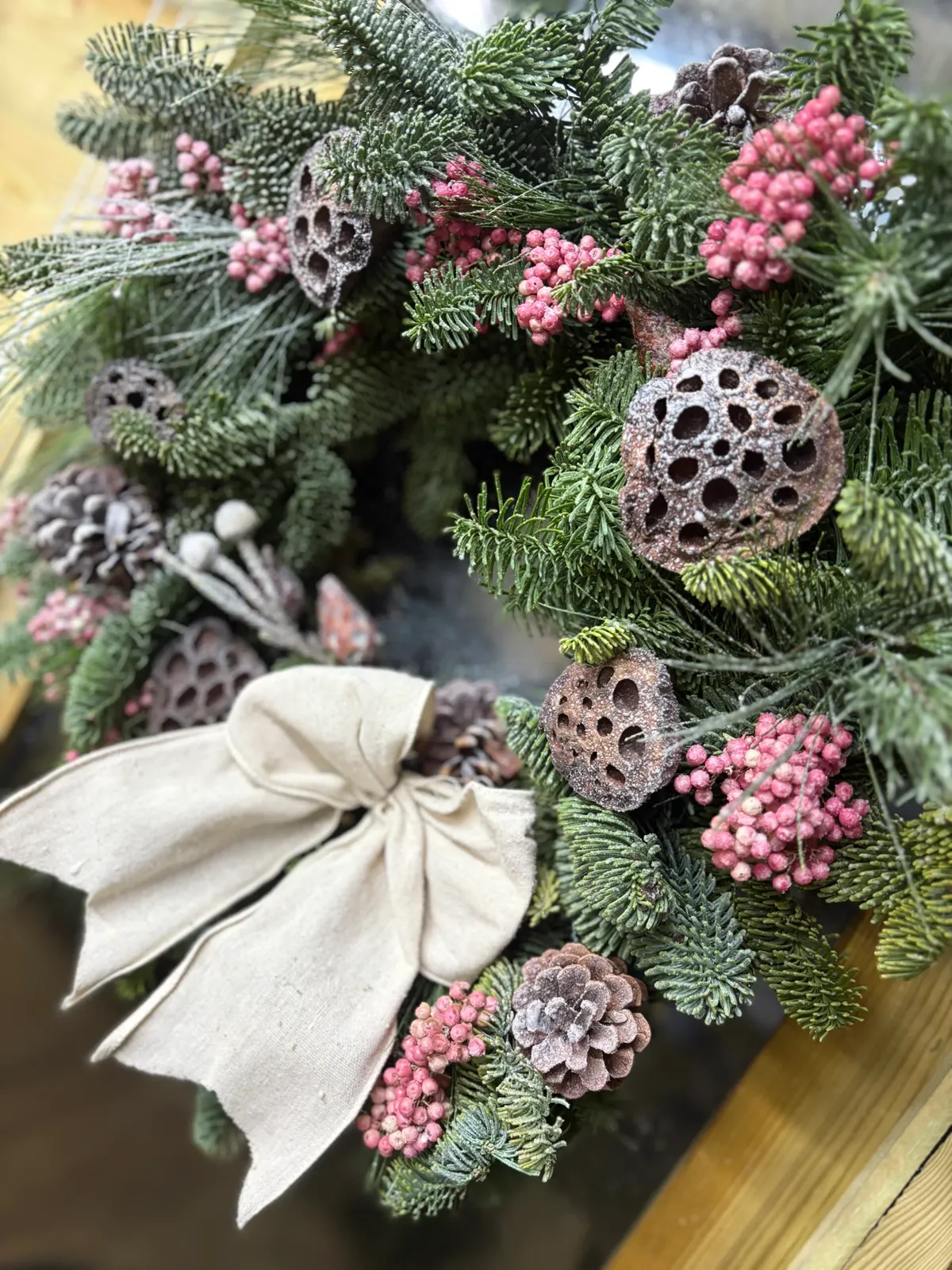 Christmas wreath with frosted lotus pods, pink peppercorns and a linen bow